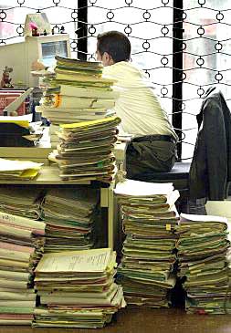Un funcionario trabaja entre montañas de expedientes en un juzgado.
