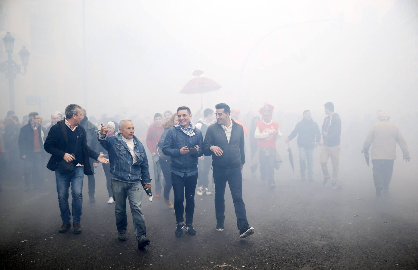 Varias personas emergen del denso humo producido por la penúltima mascletá oficial de las Fallas 2015