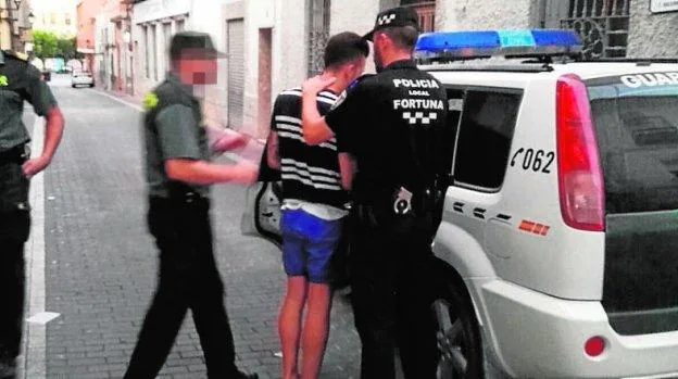 El detenido es custodiado por un policía local y un guardia civil.