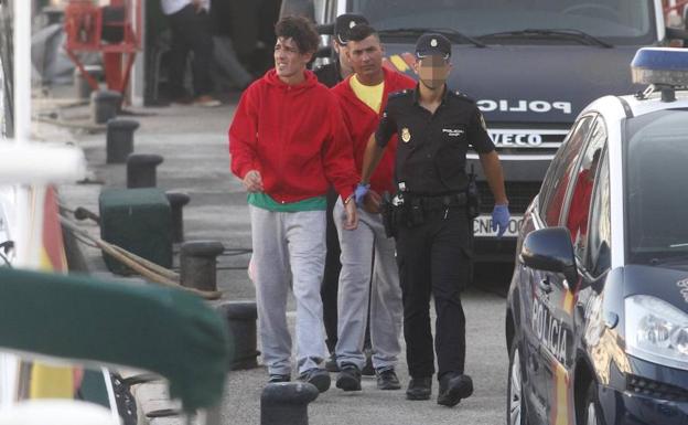 Dos inmigrantes, custodiados por agentes de la Policía Nacional, en el puerto de Cartagena.