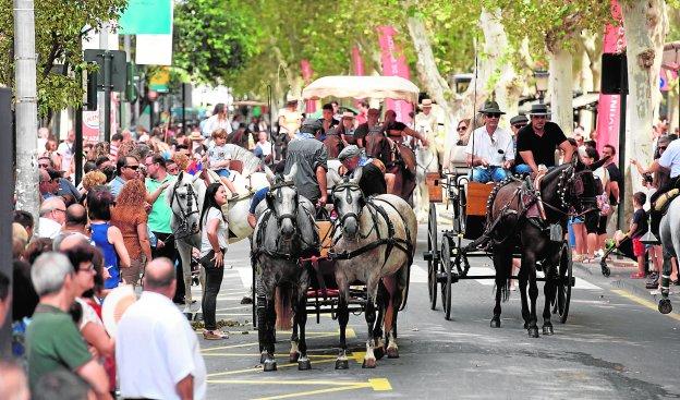 Varios carruajes recorren el paseo de Alfonso X el Sabio ante la expectación del público en ambas aceras.