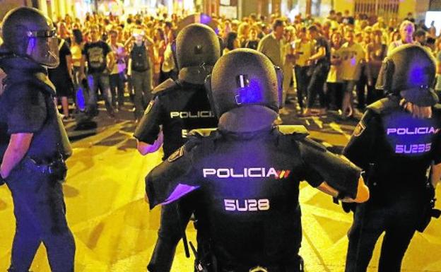 Cuatro agentes de la Policía Nacional, anoche, vigilan las vías, frente a un grupo de manifestantes