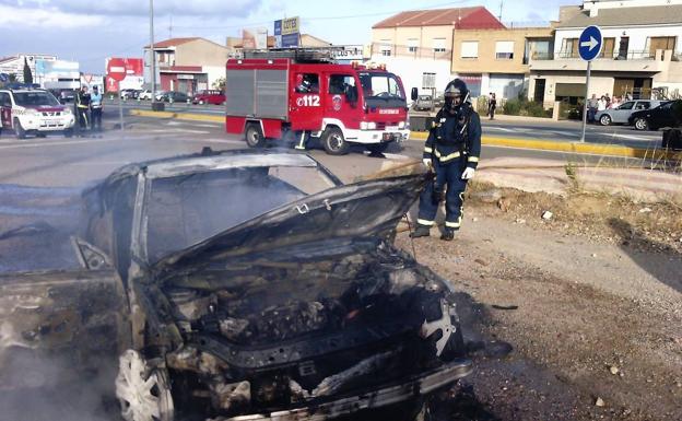 Un bombero observa el vehículo calcinado.