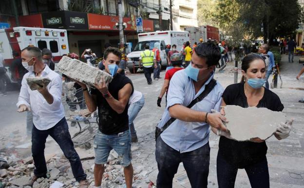 Varias personas ayudan a desescombrar tras el temblor.