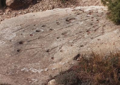 Imagen secundaria 1 - Agua embalsada en una de las cazoletas, petroglifo tallado en piedra y canaleta frente a las faldas del Monte Arabí.