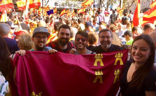 El vicepresidente de la Casa Regional de Murcia en Barcelona, José Gómez (2d), sostiene una bandera de la Región junto a otros murcianos, este domingo, en la marcha. 