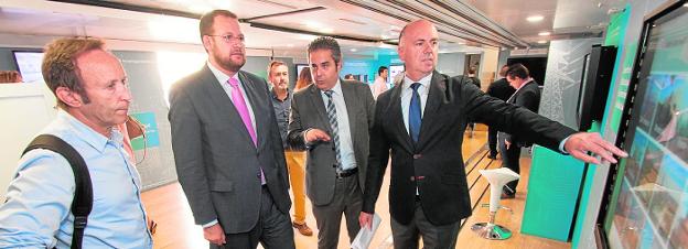 El concejal José Guillén (2º i.) recibe explicaciones de Ramón Albors (d) en el bus de Siemens. 