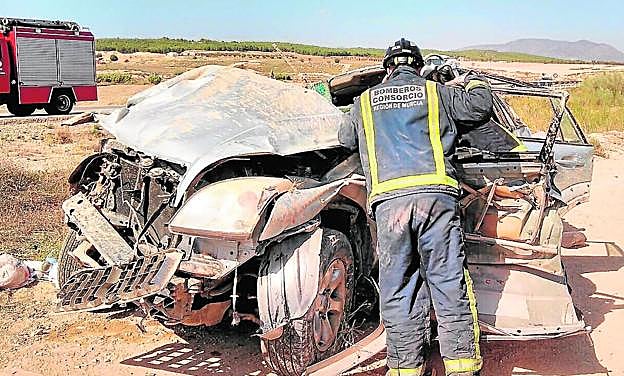 Un bombero, junto al turismo accidentado en Caravaca de la Cruz. 