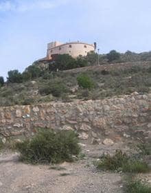 Imagen secundaria 2 - El patio interior de la fortaleza, con su pozo, una puerta acristalada de la batería de San Pedro y el castillo de Águilas, en lo alto del monte.