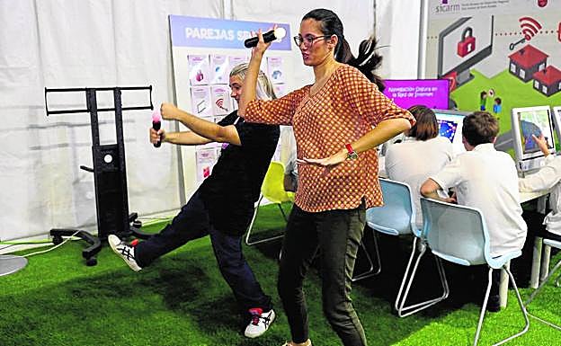 Dos asistentes juegan en la zona de ocio y entretenimiento digital con una de las videoconsolas de la feria.
