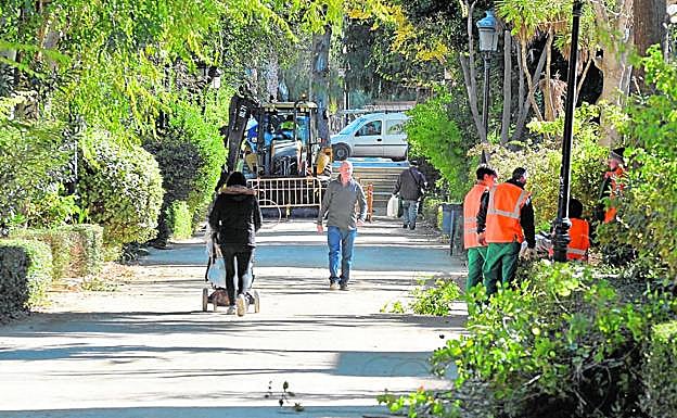 Una excavadora levanta los adoquines de los jardines mientras una cuadrilla de peones poda los setos y arbustos.