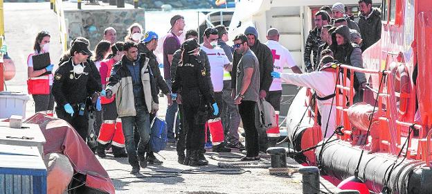 Agentes de la Policía Nacional y voluntarios de Cruz Roja reciben en el puerto de Cartagena, ayer, a un grupo de inmigrantes llegados en pateras.