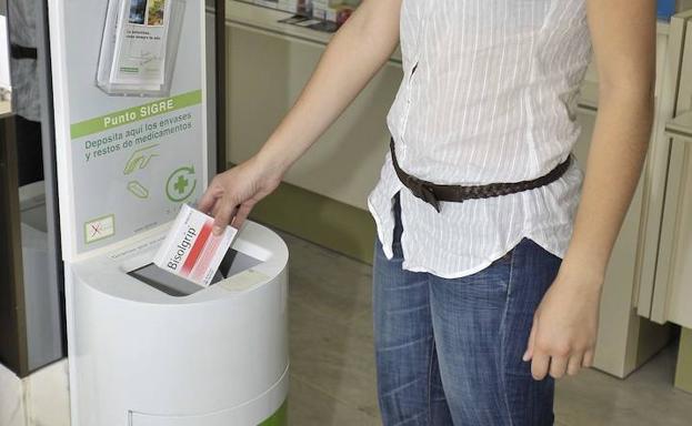 Una joven deposita un medicamento en un punto de reciclaje.