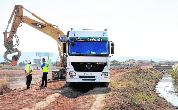 Una máquina recoge, junto a un canal de drenaje, un trozo del salmueroducto que está siendo extraído estos días por Tragsa en el Campo de Cartagena.