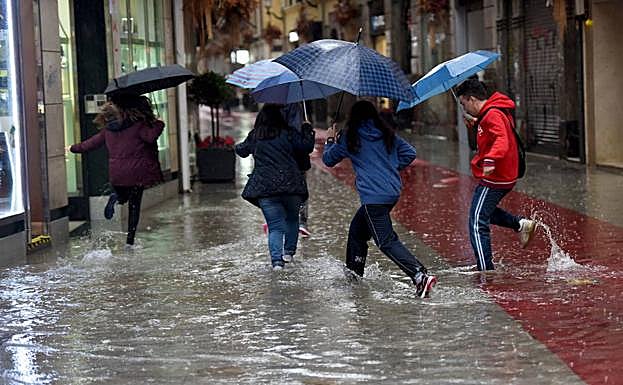 Unos jóvenes corren bajo la lluvia tras fuertes precipitaciones en la ciudad de Murcia en una imagen de archivo. 