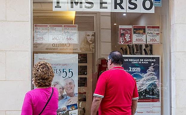 Dos personas miran en un escaparate los viajes del Imserso. 