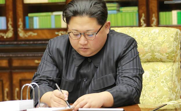 Kim Jong-un firma un documento oficial. 
