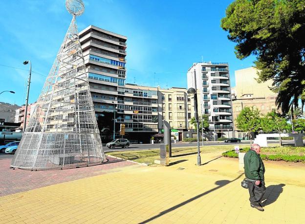 Un hombre pasa junto al árbol, en la Plaza de España.