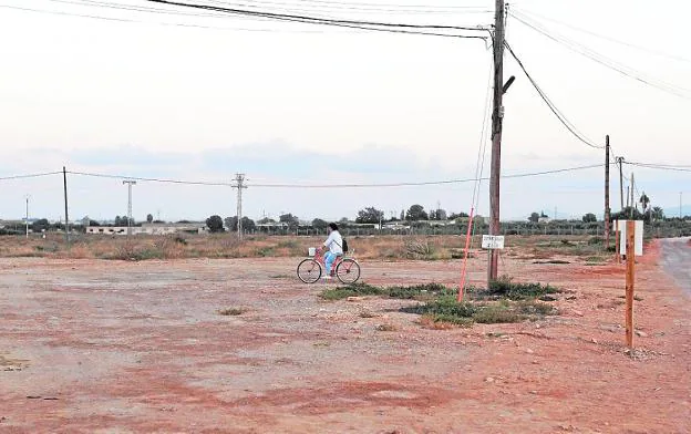 Una ciclista pasa por los terrenos donde se construirá el nuevo colegio de La Aljorra.