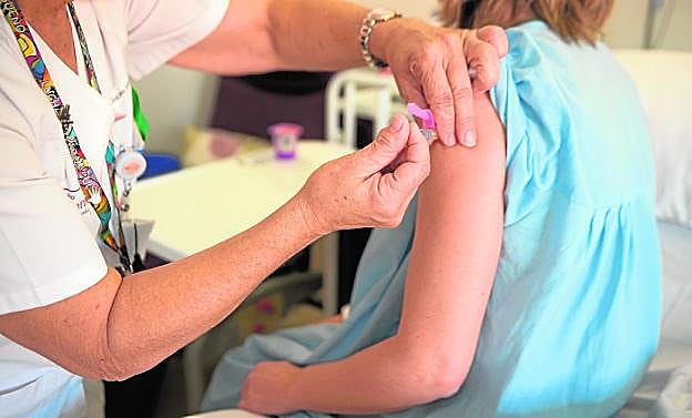 Una enfermera vacuna a una paciente ingresada en La Arrixaca, ayer por la mañana.