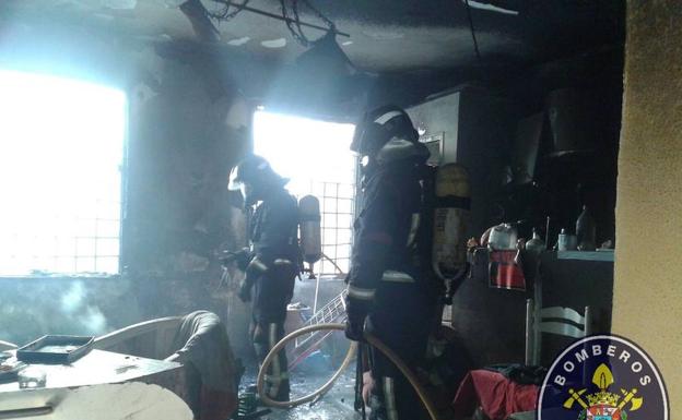 Los bomberos, ayer, en el interior de la vivienda.
