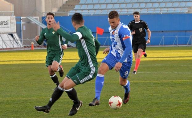 Andrés Carrasco avanza con el balón ante los jugadores del Betis Deportivo.