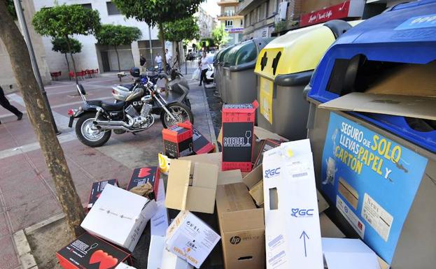 Cajas de cartón junto a unos contenedores de una calle de Murcia.