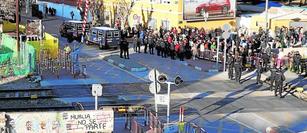 A la izquierda, entre telas amarillas, parte de las obras de la pasarela, y a la derecha, decenas de personas ayer por la tarde, ante un fuerte despliegue policial en Torre de Romo.