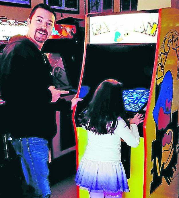 José María Litarte señala a su hija mientras juega al 'Pac Man' o 'comecocos'.