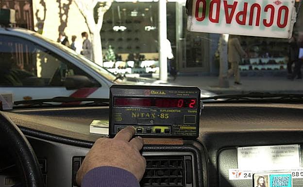 Un taxista de Murcia accionando el taxímetro de su vehículo.