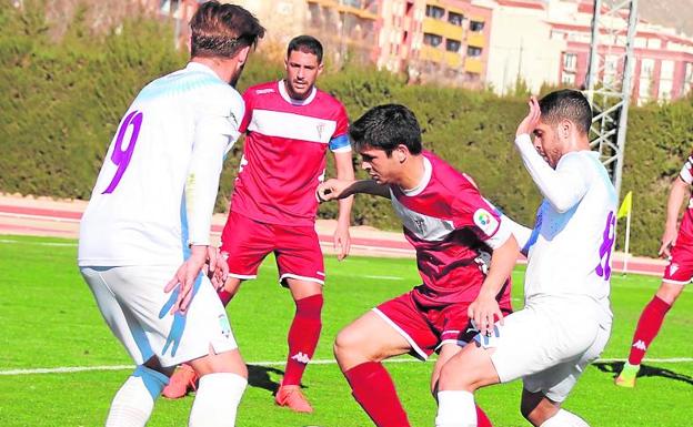 Titi y Carlos García, ambos del Jumilla, rodean a un rival.