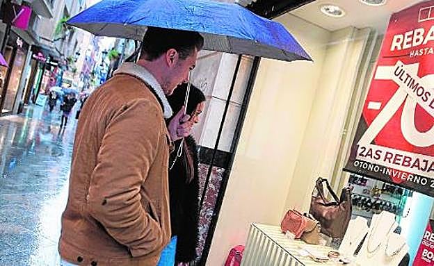 Una pareja se detiene, ayer, ante el escaparate de una tienda de la calle Platería con ofertas en los últimos días de rebajas.