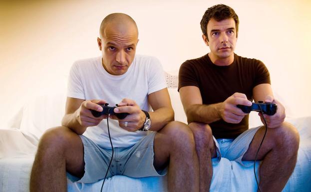Dos hombres juegan con una consola. 
