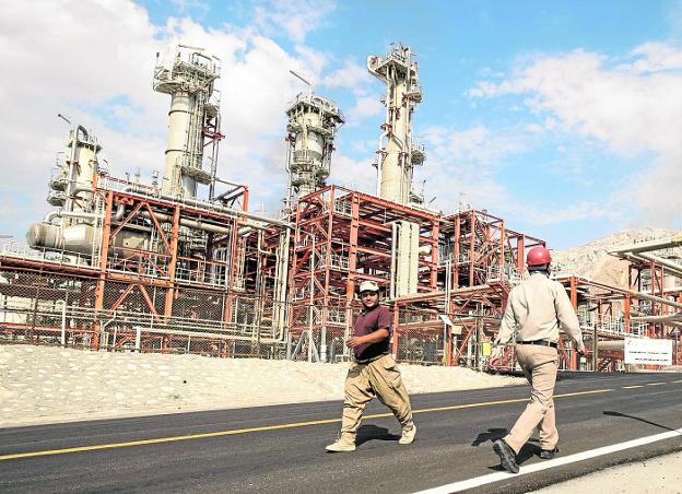 Dos trabajadores se cruzan en una refinería iraní.