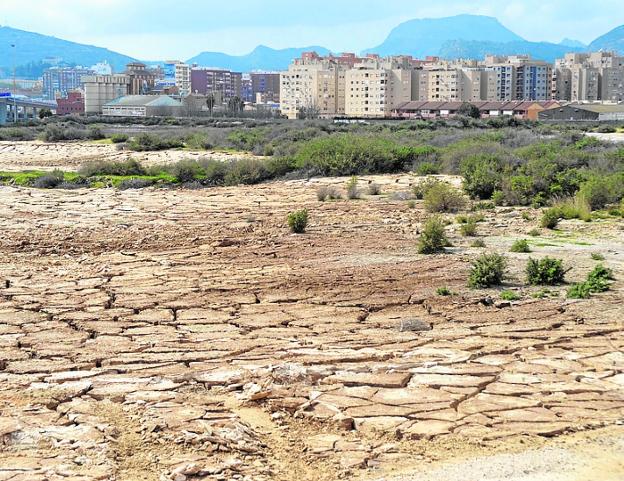 Terrenos de El Hondón, cuarteados, con la ciudad al fondo.