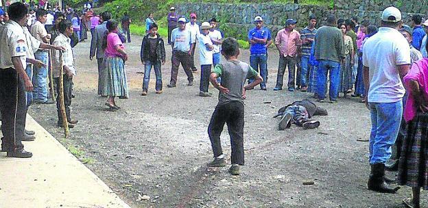 Vecinos de la localidad guatemalteca de Tactic observan el cuerpo de un asesino de niñoslinchado tras arrebatárselo a la Policía.