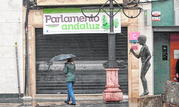 Una mujer pasa frente al local de Parlamentlo Andaluz.