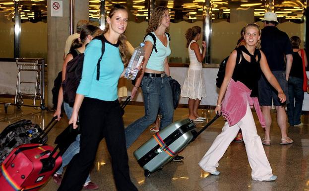 Un grupo de jóvenes arrastran sus maletas por la terminal de un aeropuerto.