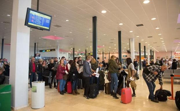 Viajeros esperan en la terminal de un aeropuerto. 