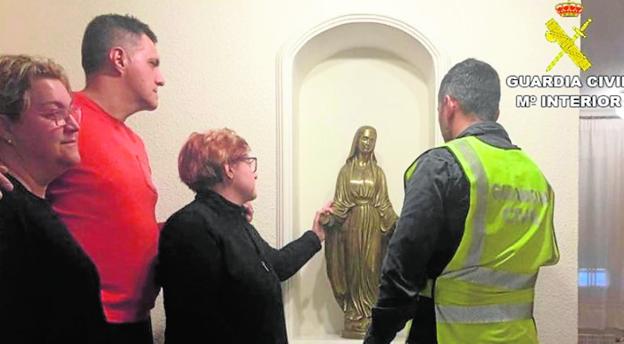 Un agente entrega una figura de la Virgen a sus propietarios. 