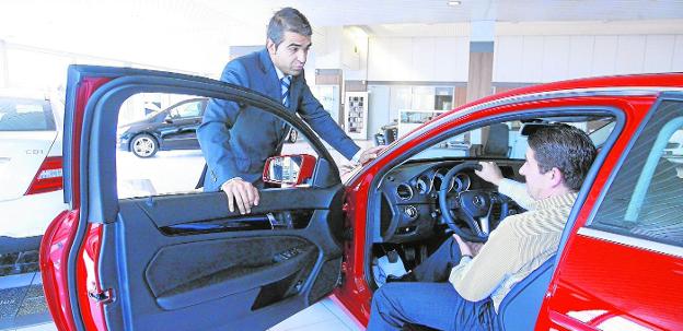 Un empresario examina un vehículo en un establecimiento de 'renting'. 