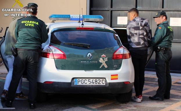 Dos guardias civiles introducen en su vehículo a los dos detenidos.
