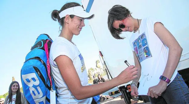 Garbiñe Muguruza firma la camiseta de Paula Pérez, una joven aficionada murciana, ayer en el centro de tenis de La Manga Club.