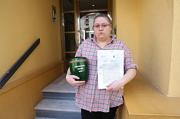 Sandra González con la denuncia interpuesta en la Policía y la urna con las cenizas de su madre, lo único que le han dado los okupas.