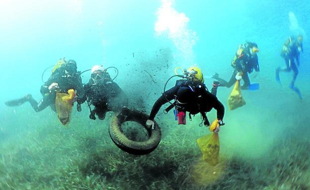 Un grupo de buceadores recoge un neumático y otros residuos del fondo del mar durante la última gran limpieza anual. 