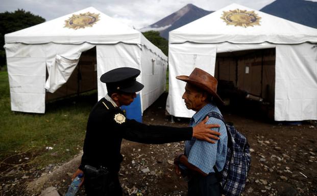 Un policía atiende a un afectado por la erupción del volcán Fuego. 