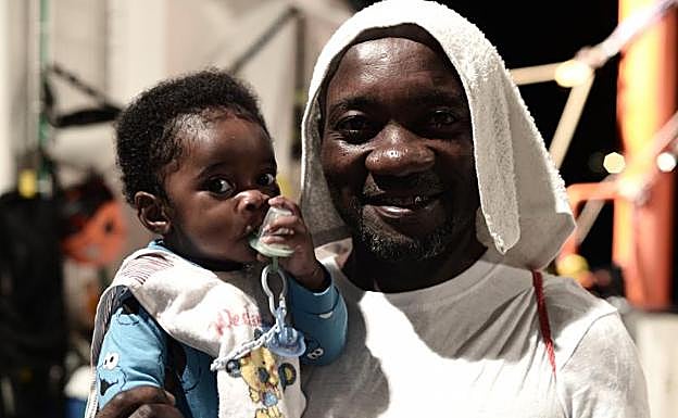 Uno de los pasajeros del 'Aquarius' sonríe a cámara mientras sostiene a un bebé.