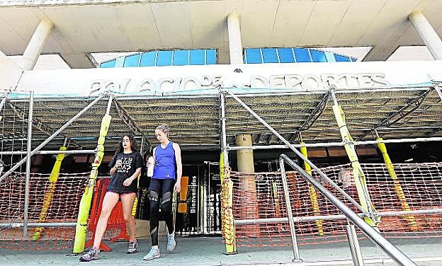 Usuarias del Palacio de Deportes, ayer, abandonando la instalación municipal, que lleva varios años protegida por andamios para evitar desprendimientos.