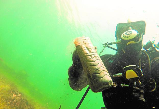 Un buceador recoge una botella del fondo del mar durante una de sus inmersiones en Cabo de Palos.