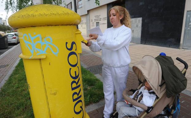 Una mujer usa un buzón de Correos en Vitoria. 